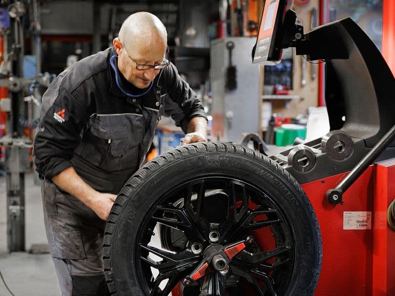 Mechaniker montiert einen Reifen an der Reifenmaschine